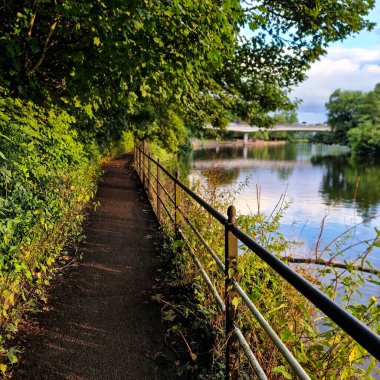 Burton-on-Trent 'te Trent nehrinin kıyısında sakin bir yürüyüş yaparak günlük hayatın koşuşturma ve koşuşturmasından huzurlu bir kaçış sunuyor. Nehrin yumuşak akışı, kuşların cıvıltısı ve yaprakların hışırtısıyla birlikte,