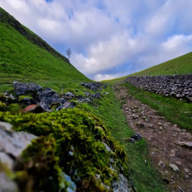 Bu görüntü üçlüsü, Dale Mağarası 'nın Peak District' teki ham ve el değmemiş ihtişamını yakalıyor. Her kare izleyiciyi, doğanın sanatının yemyeşil yamaçlarda sergilendiği bu antik kireçtaşı vadisinde bir yolculuğa davet ediyor.