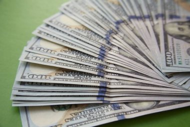 Yüz dolarlık banknotlar yeşil bulanık bir fana serilmiş.