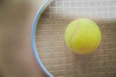 Tenis topu, açık kumlu arka planda raketin üzerinde uzanır. Tenis oynar, spor yapar.