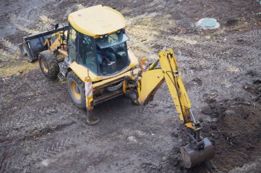 Kazı makinası toprak çalışmalarına başlıyor, bir arazi inşaatında sarı kazıcı..