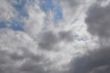 Gökteki yağmur bulutları, mavi gökyüzünün görülebildiği, gri bulutların arasından geçen ışık.