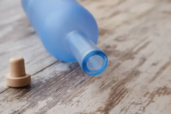 Boş bir votka şişesi ve mantarı ahşap bir masada yatıyor.