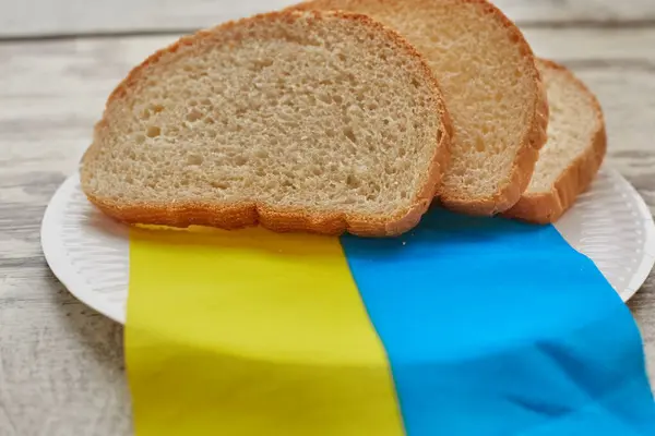 Dilimlenmiş ekmek Ukrayna bayrağında bir tabakta yatıyor, Ukrayna ekmeği ve tahılla ilgili sorunlar