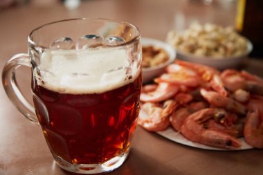 Masada karides ve fındık yanında köpüklü bir bardak bira, yakın plan, bira barı atmosferi, bira barında atıştırmalıklar.