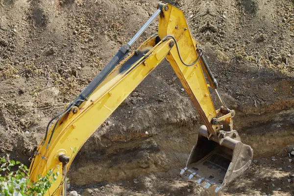 Kazı makinesinin kovası zemini kazıyor, kazıcının kovası kazı çukurunu kapatıyor, inşaat işi, çukur kazıyor.