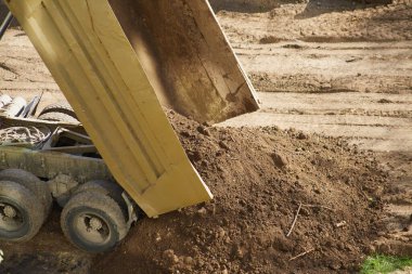Çöp kamyonunun cesedi toprağı boşaltıyor. Çöp kamyonu toprağı boşaltır, arazi inşaatı yapar.