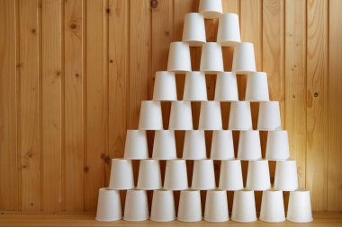 Tahta bir zeminde piramide istiflenmiş kağıt bardaklar kağıt bardaklar, tek kullanımlık bardaklar, kağıt kaplar, çevre dostu yemekler.