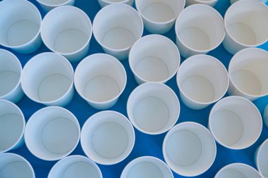 Beyaz kağıt bardaklar mavi arkaplanda durur, mavi arkaplanda tek kullanımlık bardaklar, kağıt bardakların üst görüntüsü