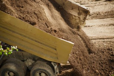Kamyon yataktan toprak boşaltıyor, kamyon yatağından toprak dökülüyor, yakın plan.