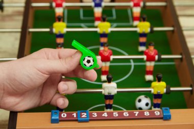 Langırt masasının arka planında futbol düdüğü tutan eller, oyun başlasın. Oyunda kural ihlali