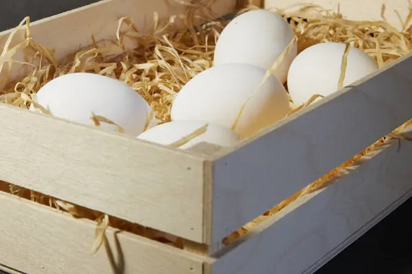 Tahta kutu tavuk yumurtaları, samanlı ahşap tavuk yumurtaları, büyük beyaz tavuk yumurtaları, yakın plan.