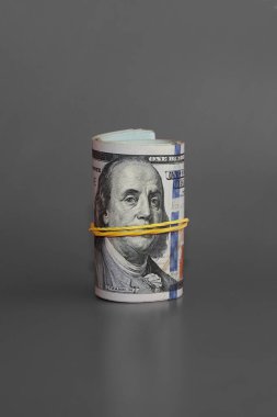 bükülmüş 100 dolarlık banknotlar, yuvarlanmış 100 dolarlık banknotlar gri bir arka planda, hesaba katılmamış nakit, para sessizliği sever, yasadışı gelir dikey çekim