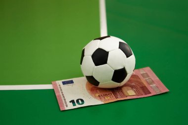 Futbol topu ve 10 avroluk banknot yeşil arka planda bir gkak, yakın plan, spor tahmini, bahisçi bahis, spor bahisleri, para oyunu üzerine bahis