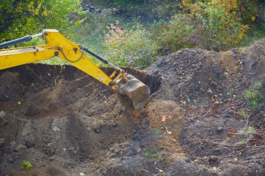 Kazıcının sağlam kovası toprağı oyuyor ve gelecekteki yapılar için bir temel oluşturuyor..