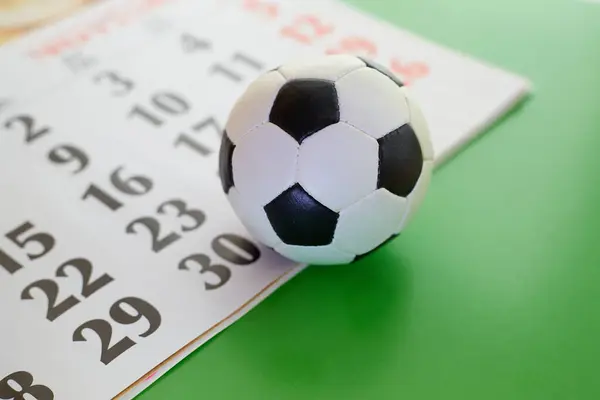 Takvimde futbol topu ve yeşil arka plan yakın plan, futbol topu yakın çekim, spor bahisleri, spor takvimi, futbol maç programı