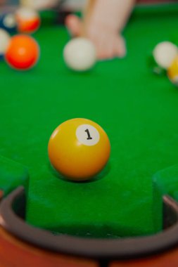 Bilardo masasının önündeki deliğin önünde bir numaralı top bilardo oynuyor, bilardo oynamaya hazırlanıyor, bilardoda sekiz numara oynuyor.