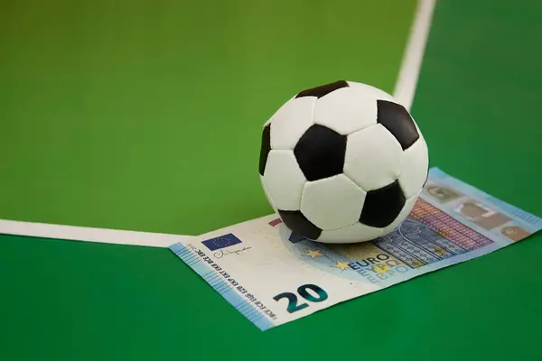 Futbol ve yeşil arka planda 20 euro banknot, spor ve para oyunlarına bahis