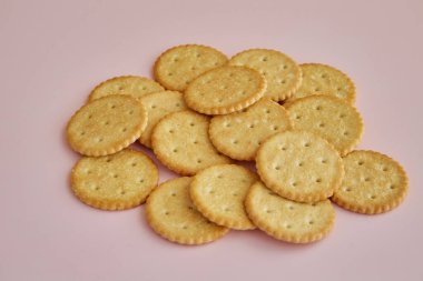 Pembe arka planda tuzlu krakerler, pembe arka planda kurabiyeler, masada kurabiyeler.