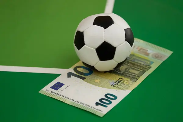 Futbol topu ve yeşil arka planda 100 euro banknot, spor bahisçisi bahis, spor bahisleri