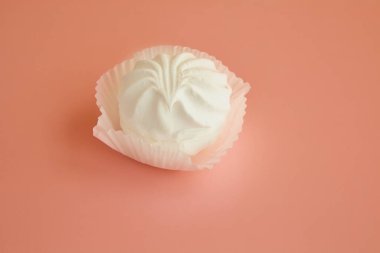 Pembe arka planda beyaz marşmelov, pembe masadaki kağıt tartta beyaz lokum..