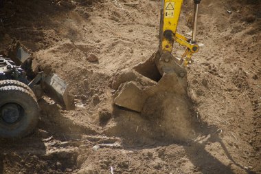Kazıcının güçlü kovası zemini kesiyor.,