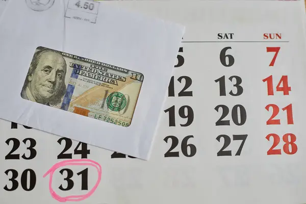Takvim 31. ve dolar banknotlarını bir posta zarfında işaretledi. Yakın çekim, para havalesi, posta çeki, finansal ödemeler.