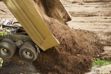 Bir kamyon, boşaltma mekanizmasını eylem halinde gösteren bir yığın toprak salıyor..