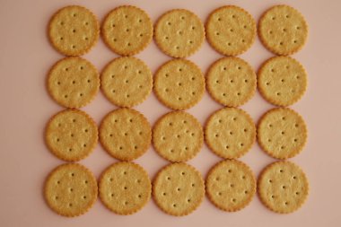 Pembe arka planda tuzlu krakerler, masada kurabiyeler, taze kurabiyeler, üst manzara.