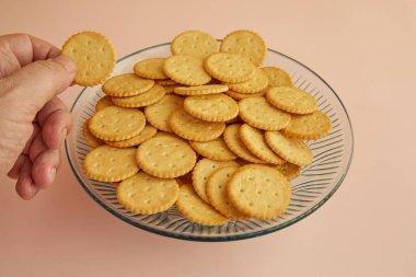 Bir el, pembe arka plandaki bir vazo kurabiyeden kraker alır, yakın plan, taze pişmiş kurabiyeler, narin kurabiyeler.