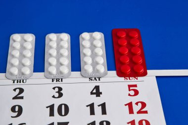 Haftanın günlerinde takvime yerleştirilmiş kabarcık hapları, ilaç hatırlatıcıları, tedavi zamanı, önleyici tedaviler, günlük haplar.