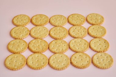 Pembe arka planda tuzlu krakerler, masada kurabiyeler, taze kurabiyeler.