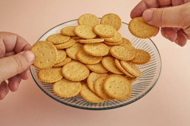 Eller, pembe arka plandaki bir vazo kurabiyeden kraker alır.