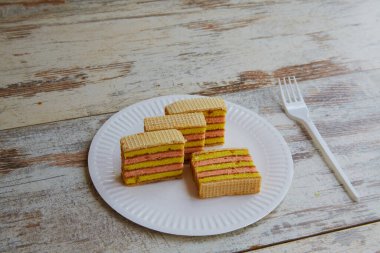 Tahta bir masada çatalla beyaz bir tabakta çoklu katmanlı kek dilimleri..