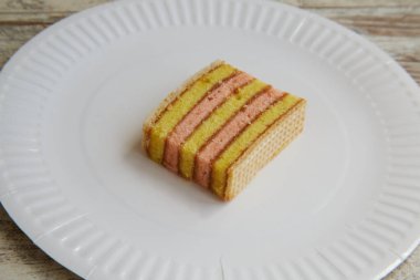 Sarı ve pembe pandispanya, waffle ve reçel ile yakın plan beyaz tabakta.