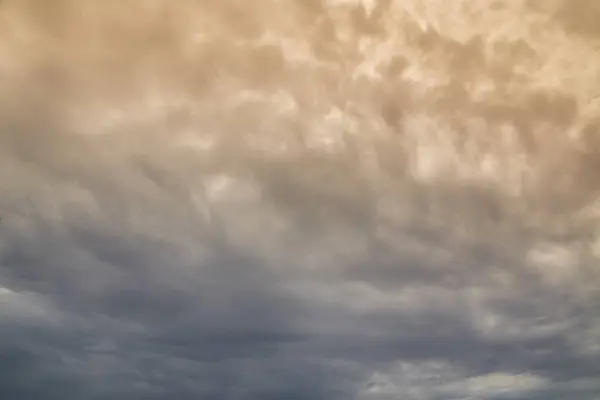 Yağmur bulutları gökyüzünü kaplıyor, bulutların arasından güneş ışığı, bulutların yoğun kefeninden ışık geçiyor.