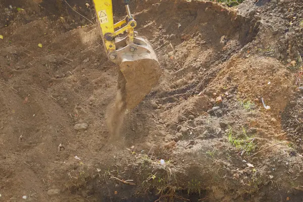 İnşaat alanının yakınındaki kazıcı kovası toprağa gömülmüş. 