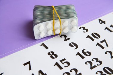 Bir takvime bağlı beyaz hapların kabarcıkları, takvim, takvim ve ilaç zamanlaması, ilaç terapisi.