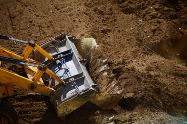 Buldozer kovası toprağı kazıyor, buldozer kovası toprağı kazıyor, buldozer kazıyor, toprak işliyor, buldozer kovası inşaat alanını temizliyor.