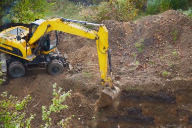 Kazı makinesi bir kova ile kazı yapıyor, kazı kovası inşaat alanında çalışıyor.
