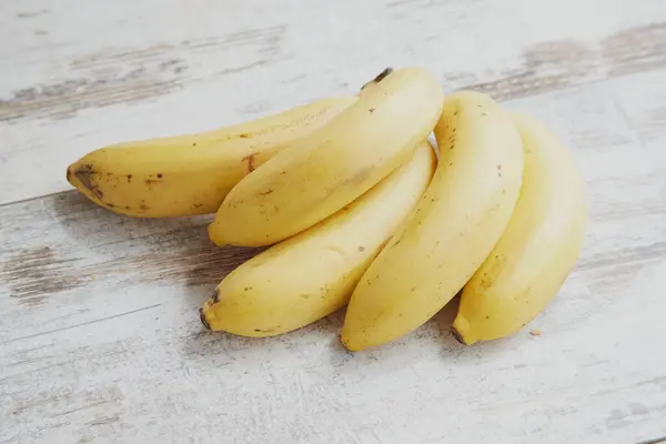 Beyaz ahşap bir masada olgun sarı muzlar. 
