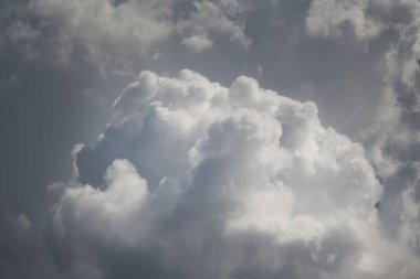 Gri bulutun arka planında büyük beyaz bulut, beyaz bulutların üzerinde güneş ışığı, bulutların üzerinde ışık oyunu, bulutların içinde, bulutların içinde, gökyüzü manzarası ve beyaz bulutlar.