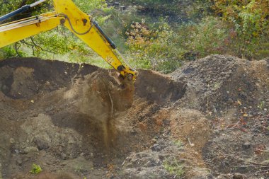 Kazıcı, toprak yığınlarını toplar ve manzarayı şekillendirir..