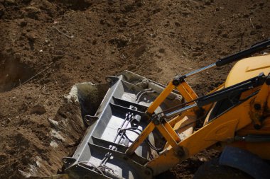 Toprakla çalışan buldozer kovasına yakın çekim, kazılar, inşaat alanındaki buldozer kovası