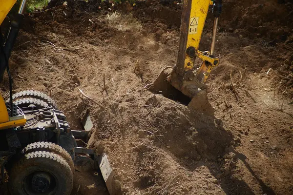 İnşaatın ilk aşamasında toprağı kepçeleyen bir inşaat kazıcı kovasının yakın çekimi..