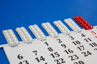 Haftanın günleri olarak belirlenen tablet kabarcıkları mavi bir takvimde, hap saatlerinde, düzenli tıbbi prosedürlerde, günlük hap alımında, ilaç hatırlatıcılarında...