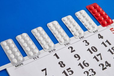 Benzer hapların kabarcıkları haftanın günleri gibi mavi arka planda bir takvimde, ilaç alma zamanı, düzenli tıbbi prosedürler, günlük hap alımı.