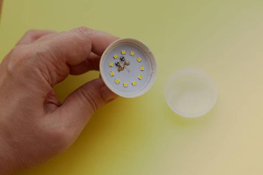 Sarı zemin üzerinde yanmış bir LED lamba, lamba hasarı, LED lamba onarımı, LED lamba üretim hatası, düşük kalite ve ucuz LED lambalar.