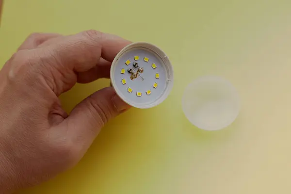 Sarı zemin üzerinde yanmış bir LED lamba, lamba hasarı, LED lamba onarımı, LED lamba üretim hatası, düşük kalite ve ucuz LED lambalar.