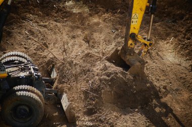 Kazıcı, yakın çekimde kovayla toprağı kepçeledi. İnşaatın ilk aşamasında toprak çalışması yaptı..
